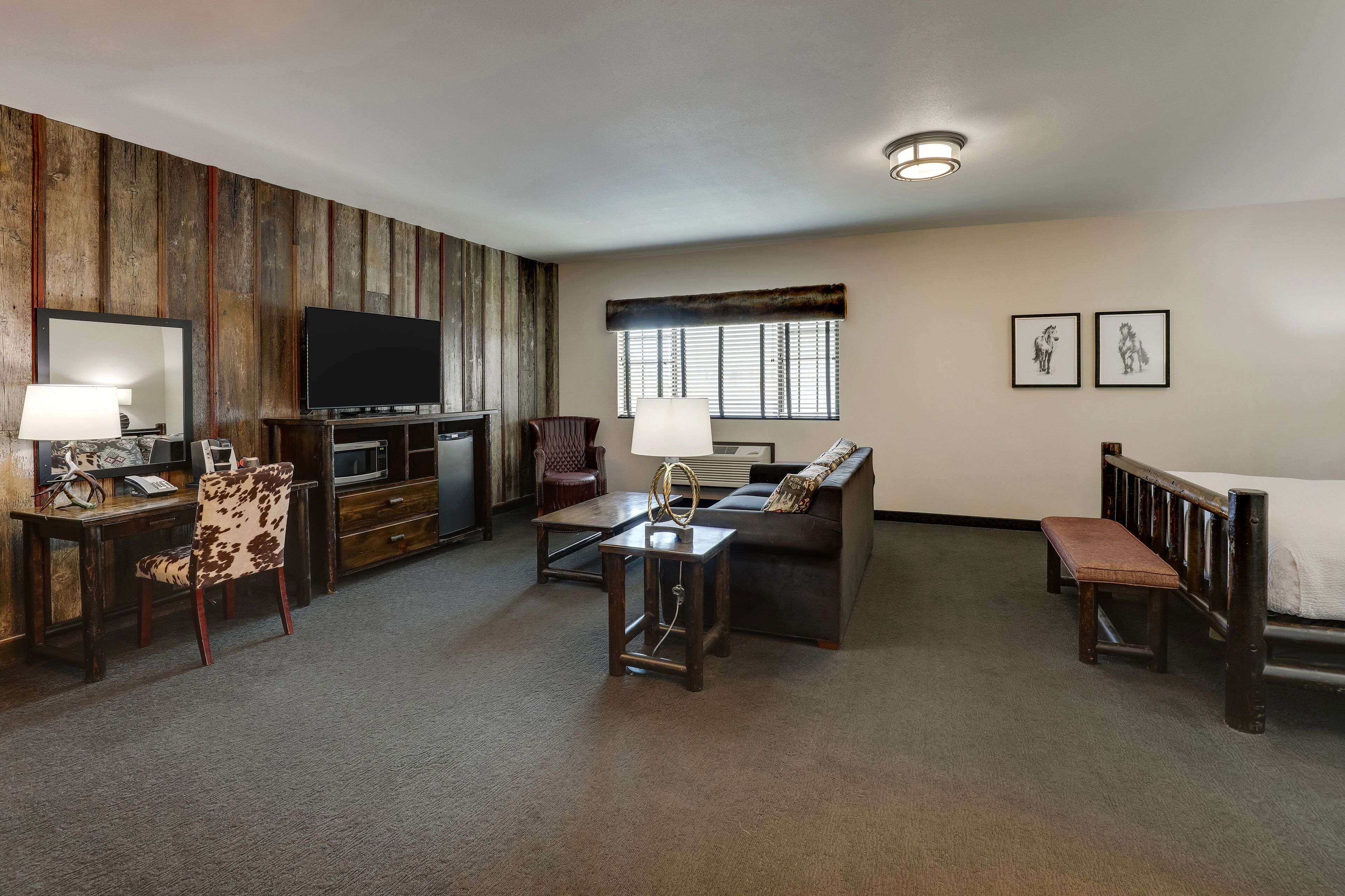 A living room with a TV, sofa, coffee table, and a wooden accent wall.