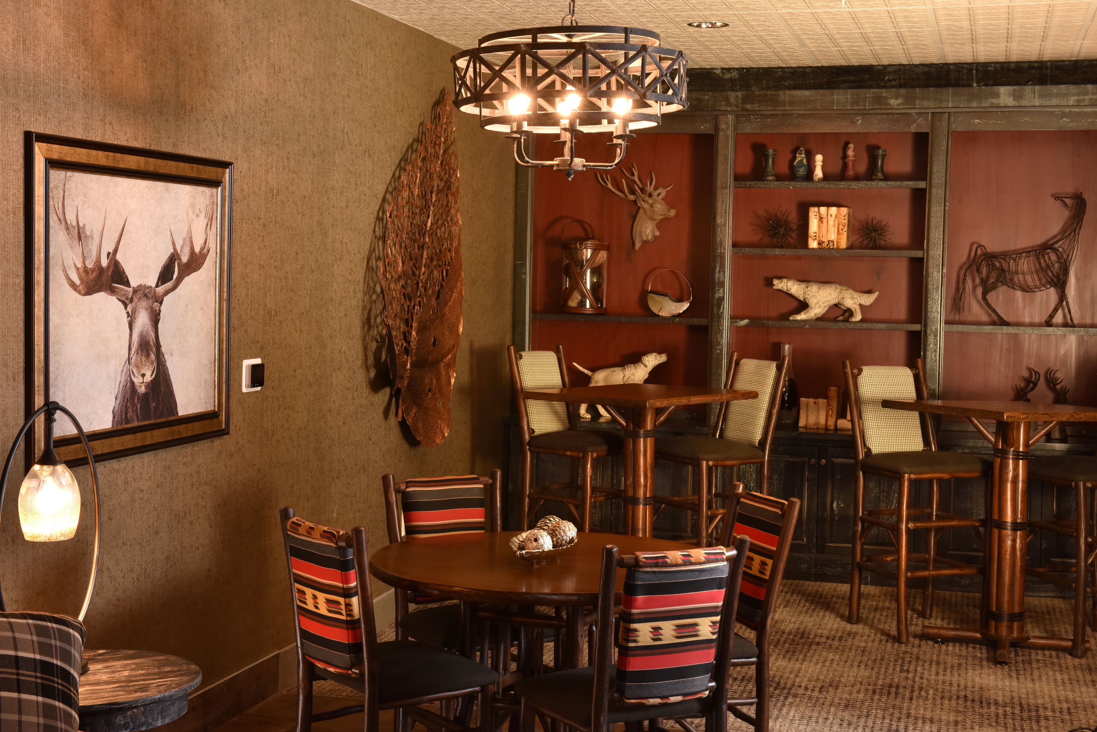 A dining area with a wooden table and chairs, a chandelier, and wall-mounted animal taxidermy.