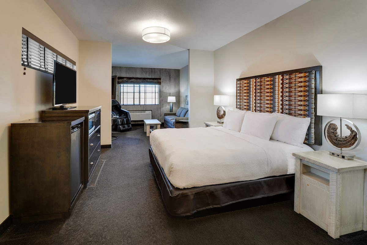 Una habitación de hotel con una cama grande, un escritorio, una silla, un televisor y un aparador.