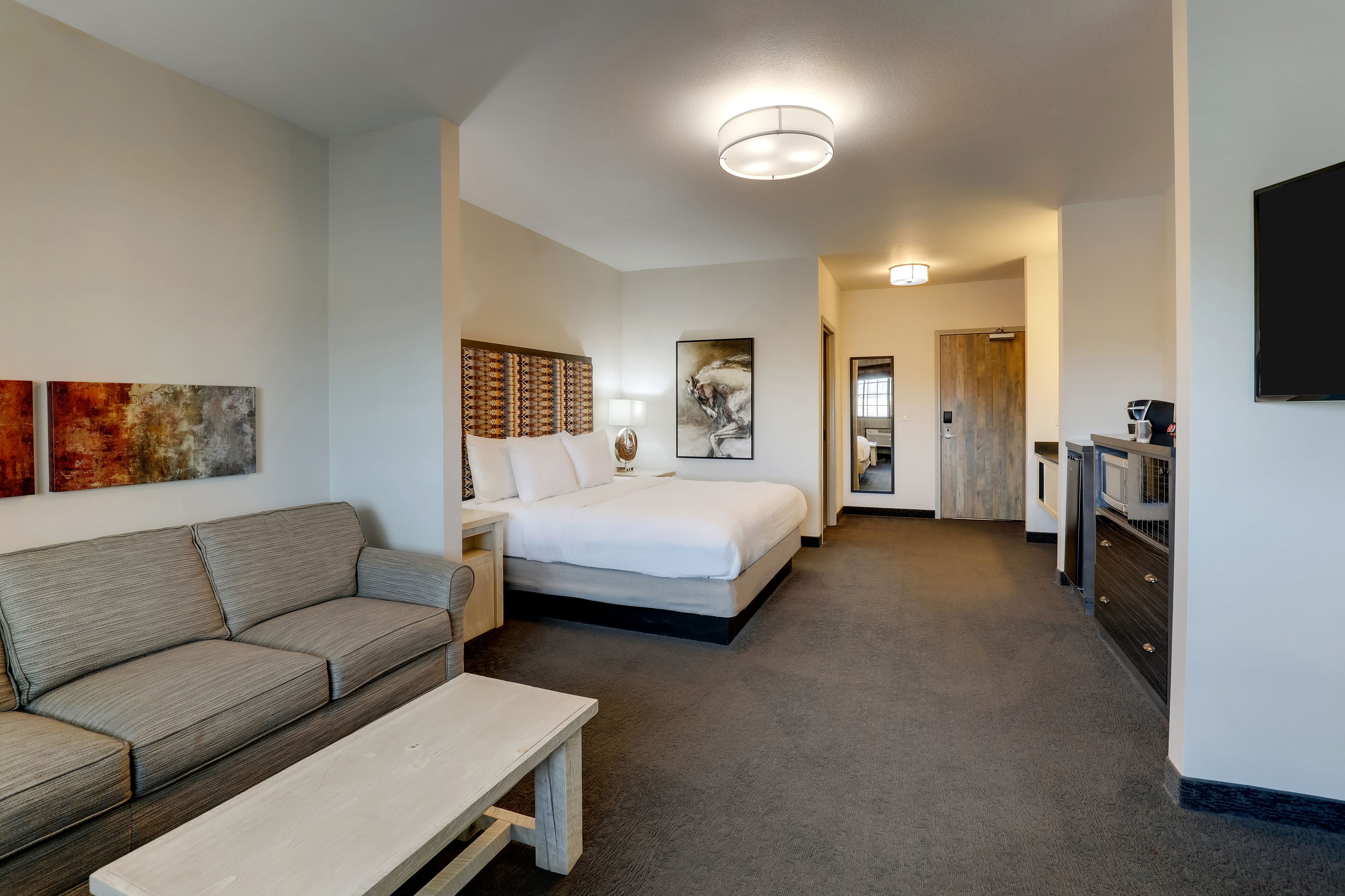 A modern hotel room with a sofa, a bed, a desk, and a TV.