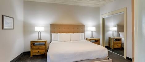 A neatly arranged hotel room with a large bed, two bedside tables with lamps, a ceiling fan, and a large mirror on the wall.