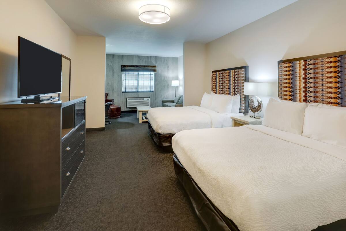 Habitación de hotel con dos camas, un televisor de pantalla plana, un escritorio y una silla.