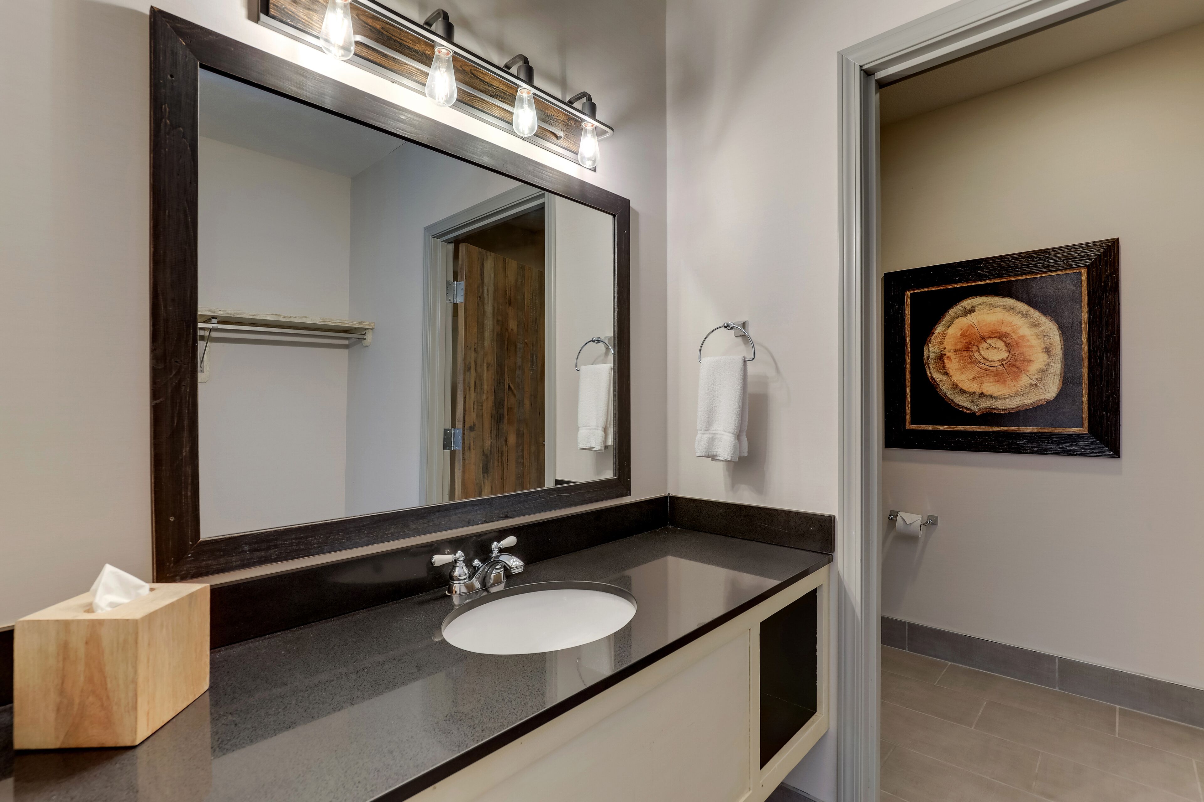 Un baño con un espejo grande, un lavabo y un perchero para toallas.