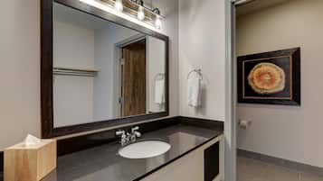 Un baño con un espejo grande, un lavabo y un perchero para toallas.