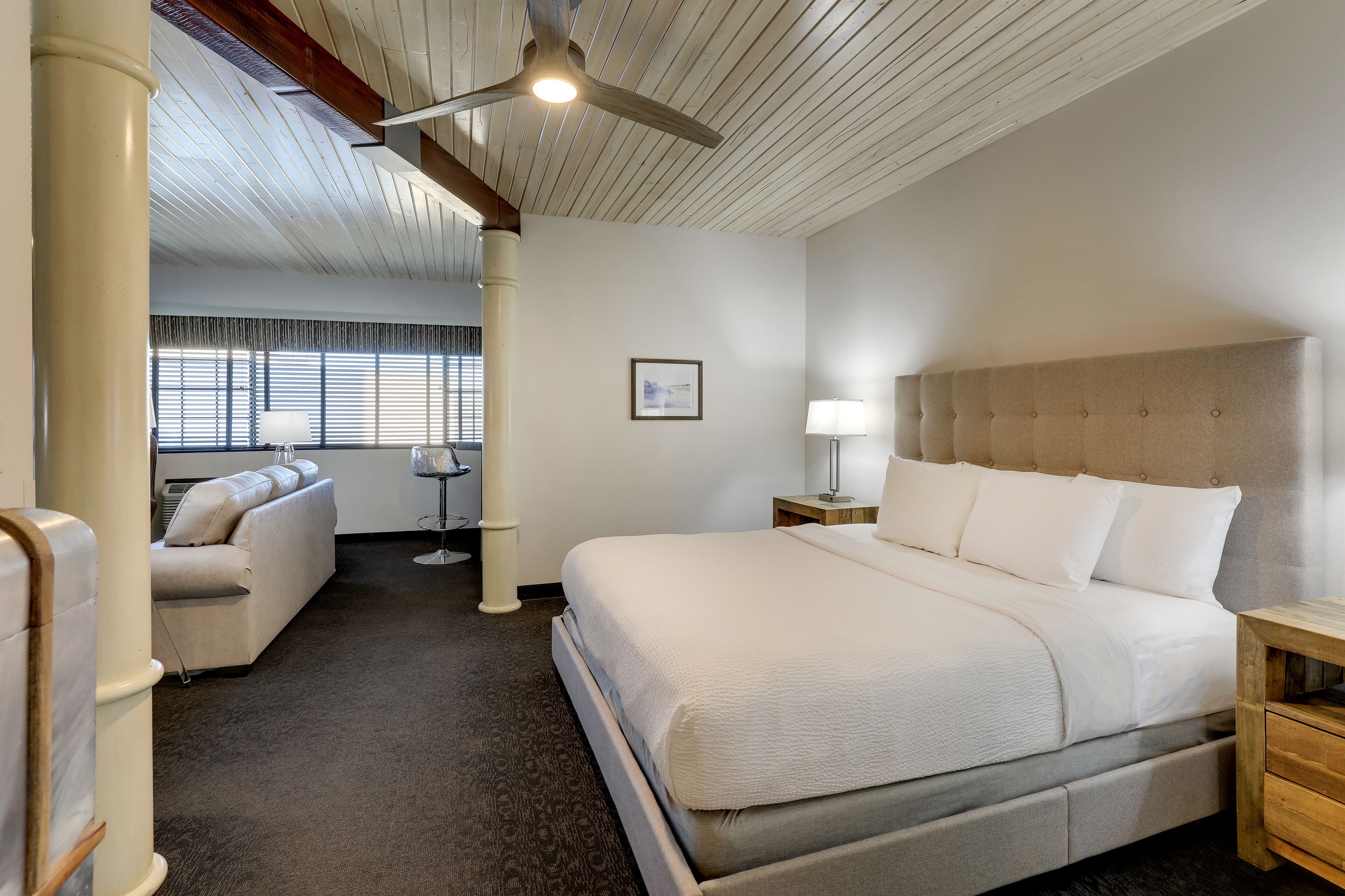 Una camera d'albergo con un letto grande, un divano, una scrivania e una ventola a soffitto.