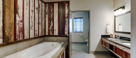A bathroom with a large bathtub, a double sink vanity, and a mirror.
