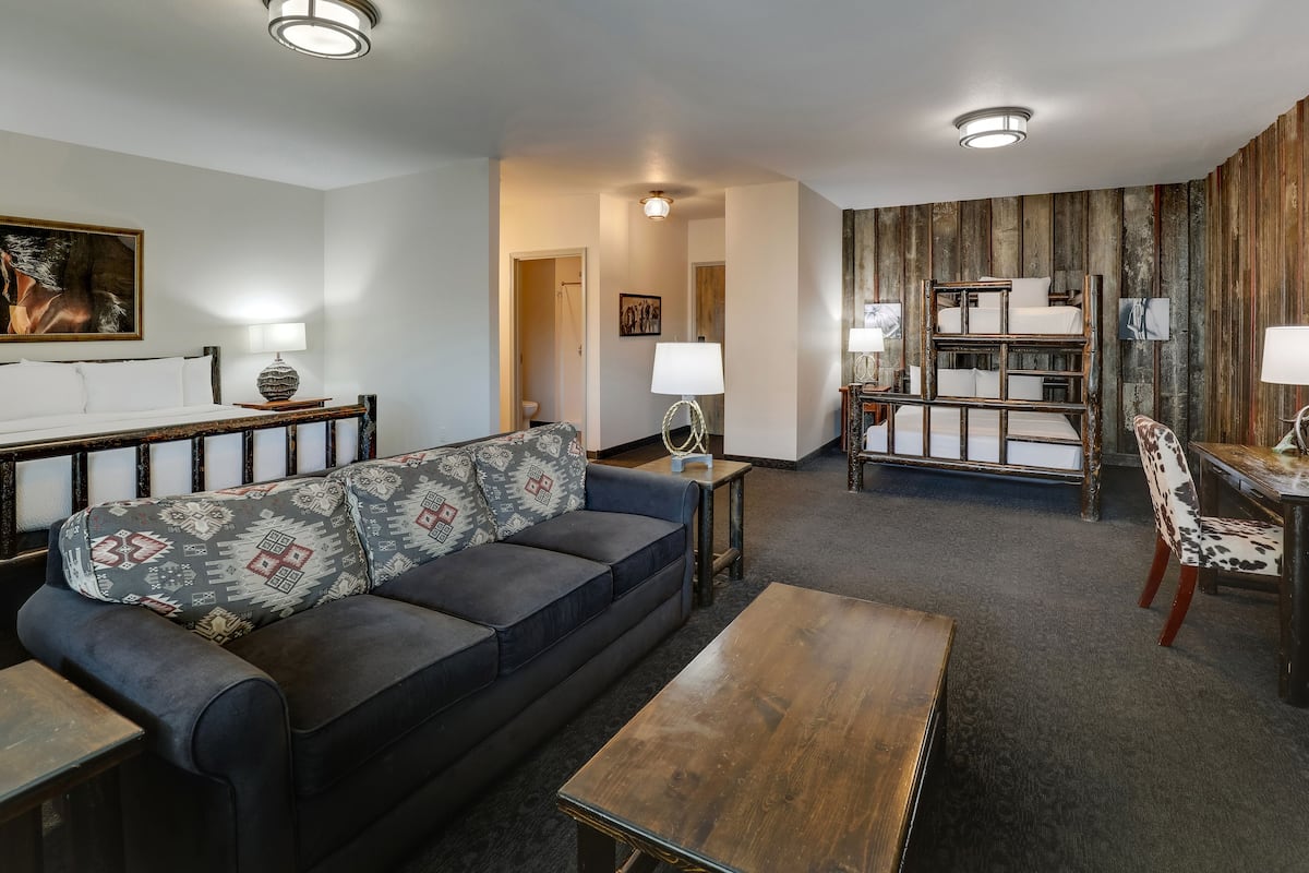 Una sala de estar moderna con sofá, mesa de centro y una cama litera al fondo.