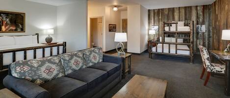 Una sala de estar moderna con sofá, mesa de centro y una cama litera al fondo.