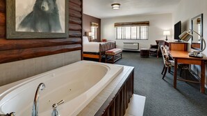 Une chambre d’hôtel avec une grande baignoire, un lit, un bureau et un téléviseur.