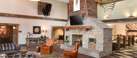 A spacious living area with a stone fireplace, leather seating, and a mounted television.