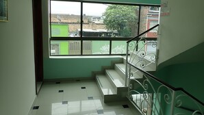 Un escalier avec une rampe en métal et une vue sur l’extérieur grâce à une grande fenêtre.