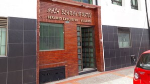 L’entrée d’un hôtel, avec une enseigne indiquant « HÔTEL CASA BLANCA » et « SERVICE EXCLUSIF POUR VOYAGEURS ».