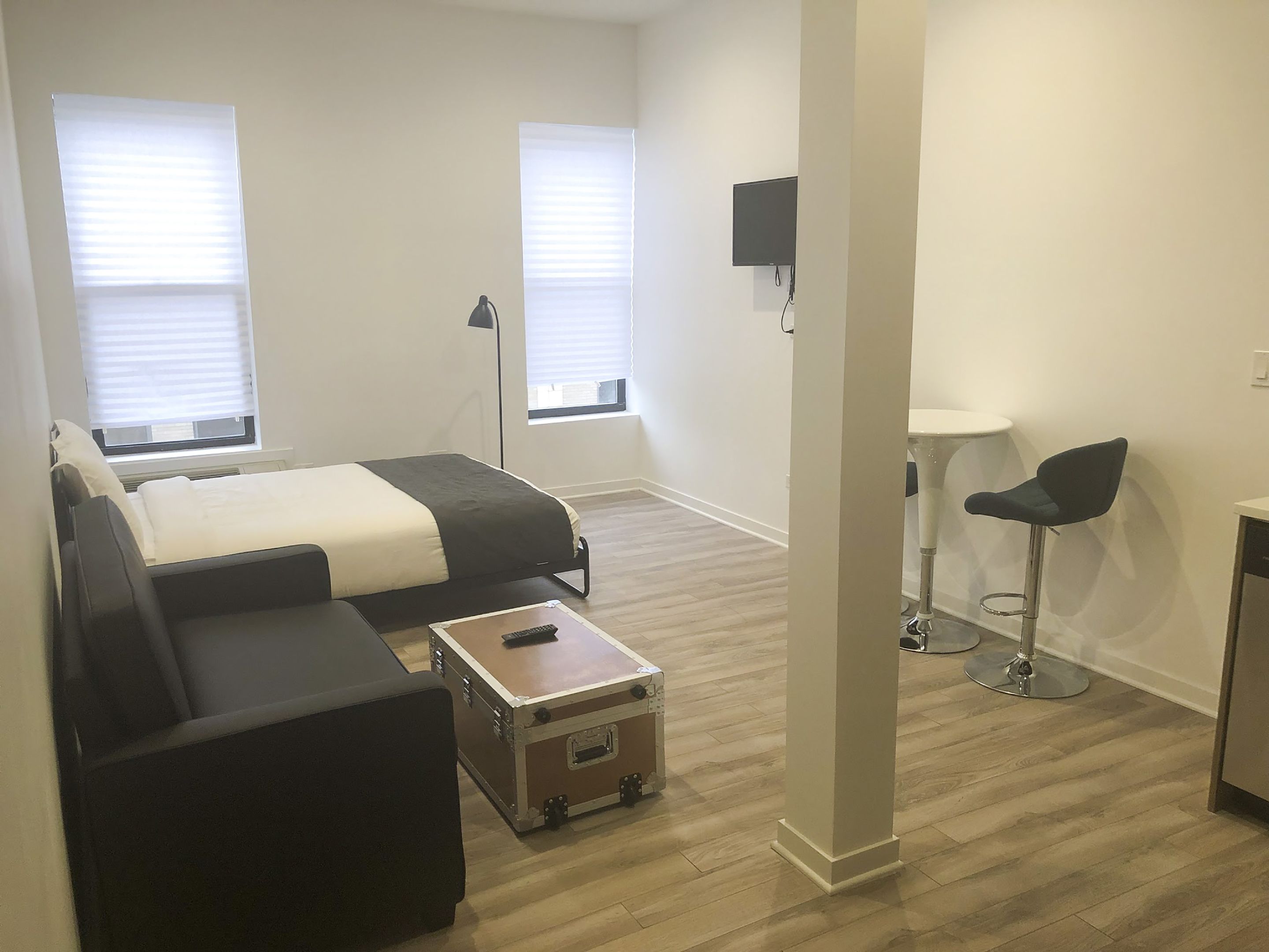 Une chambre d’hôtel moderne équipée d’un lit, d’un canapé, d’une petite table, d’une télévision et d’un bureau.