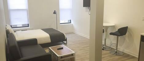 Une chambre d’hôtel moderne équipée d’un lit, d’un canapé, d’une petite table, d’une télévision et d’un bureau.