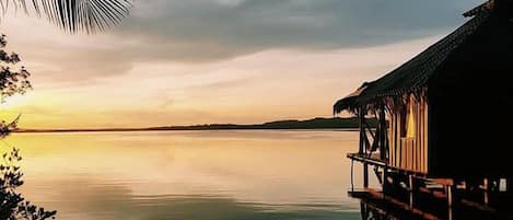 Una vista tranquila del lago con una estructura de techo de paja que se extiende sobre el agua.