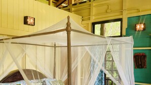 Una habitación con cama con dosel, dosel y vistas a la vegetación.