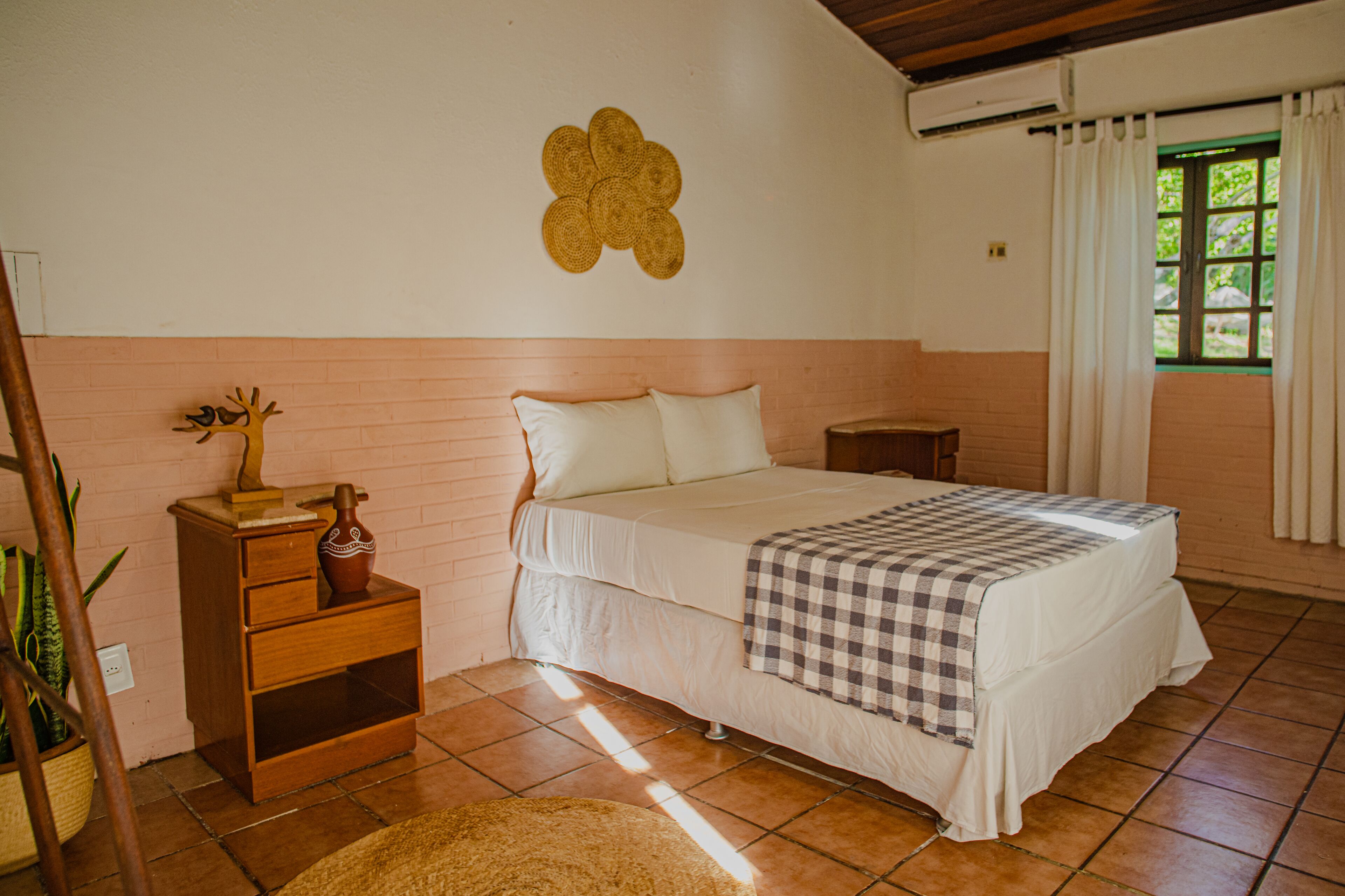 A bedroom with a bed, bedside tables, a wall-mounted decoration, and a window with curtains.