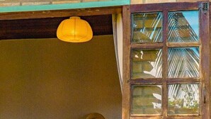 Ein Zimmer mit Fenster, einer Hängelampe und einer Pflanze.