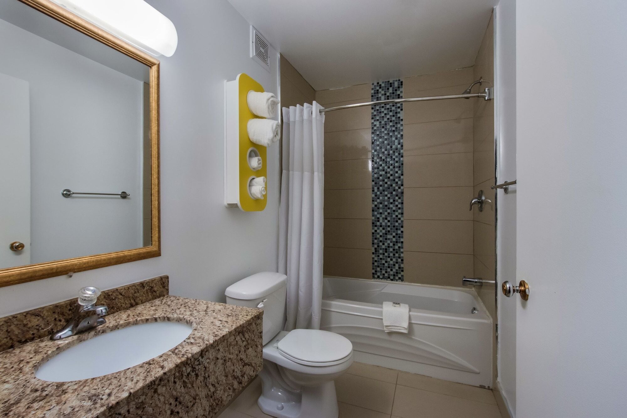 A bathroom with a granite sink, white toilet, and a shower with a glass door.