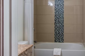 Une salle de bain avec une baignoire, un rideau de douche et des murs carrelés.