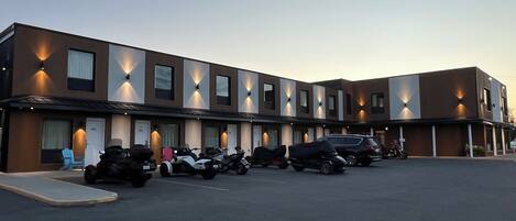 A modern hotel with a row of rooms and a parking area.