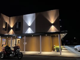 Un edificio de diseño moderno, con un cartel que indica la recepción y una motocicleta estacionada en la entrada.