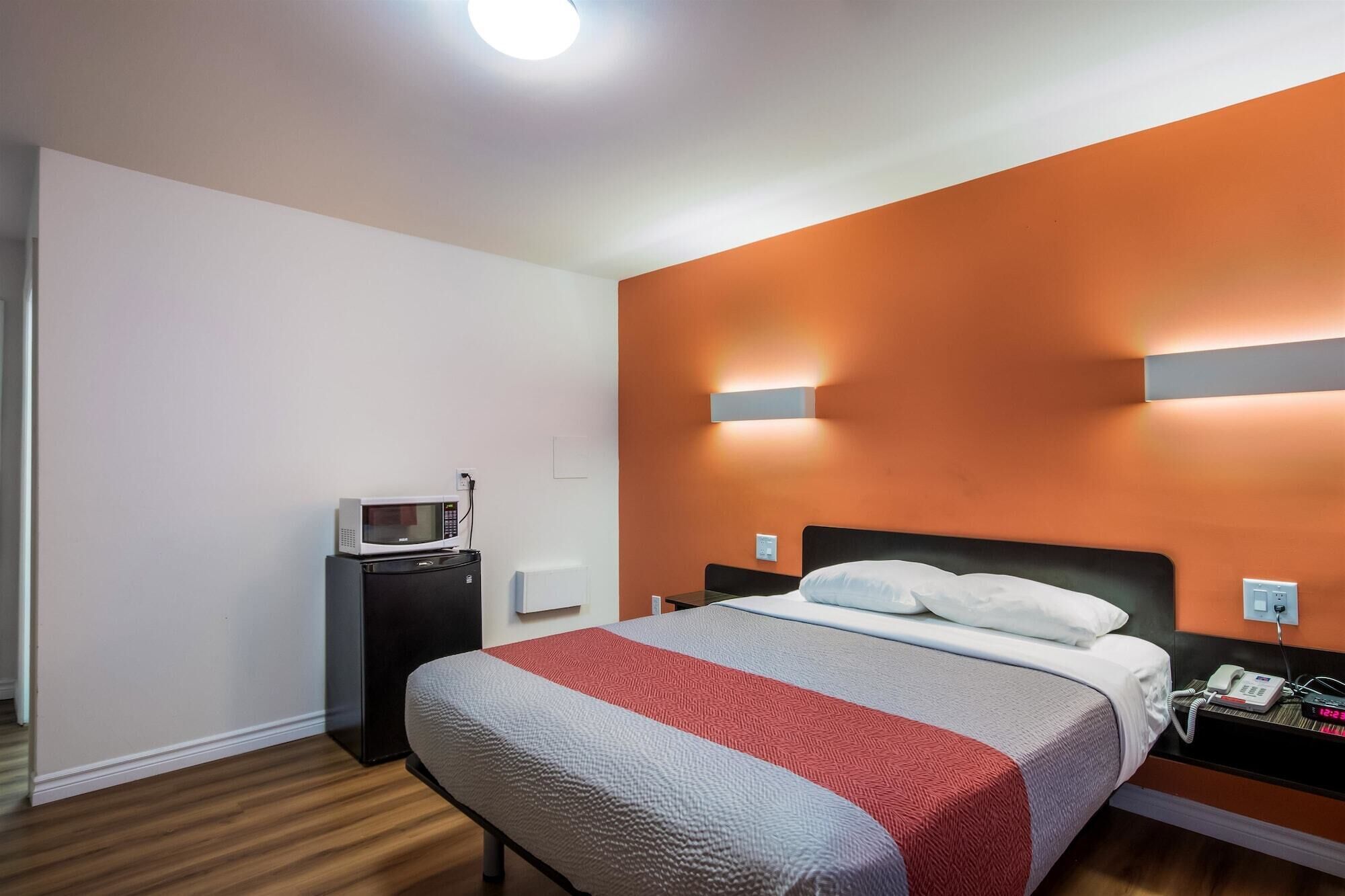 Een hotelkamer met een bed, een nachtkastje met telefoon, een magnetron en een bijzettafeltje.