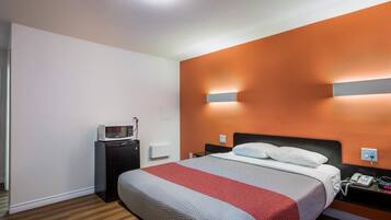 Een hotelkamer met een bed, een nachtkastje met telefoon, een magnetron en een bijzettafeltje.