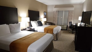 A hotel room with two beds, a desk, a chair, a TV, and a window with curtains. - False River Hotel  (New Roads)
