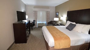 A hotel room with a bed, desk, chair, TV, and lamps. - False River Hotel  (New Roads)