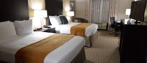 A hotel room with two beds, a desk, a chair, a TV, and a window with curtains.
