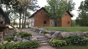 A cabin with a stone foundation, wooden exterior, and a stone staircase leading to the entrance.