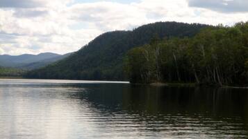 A calm lake with a forested hill in the background.