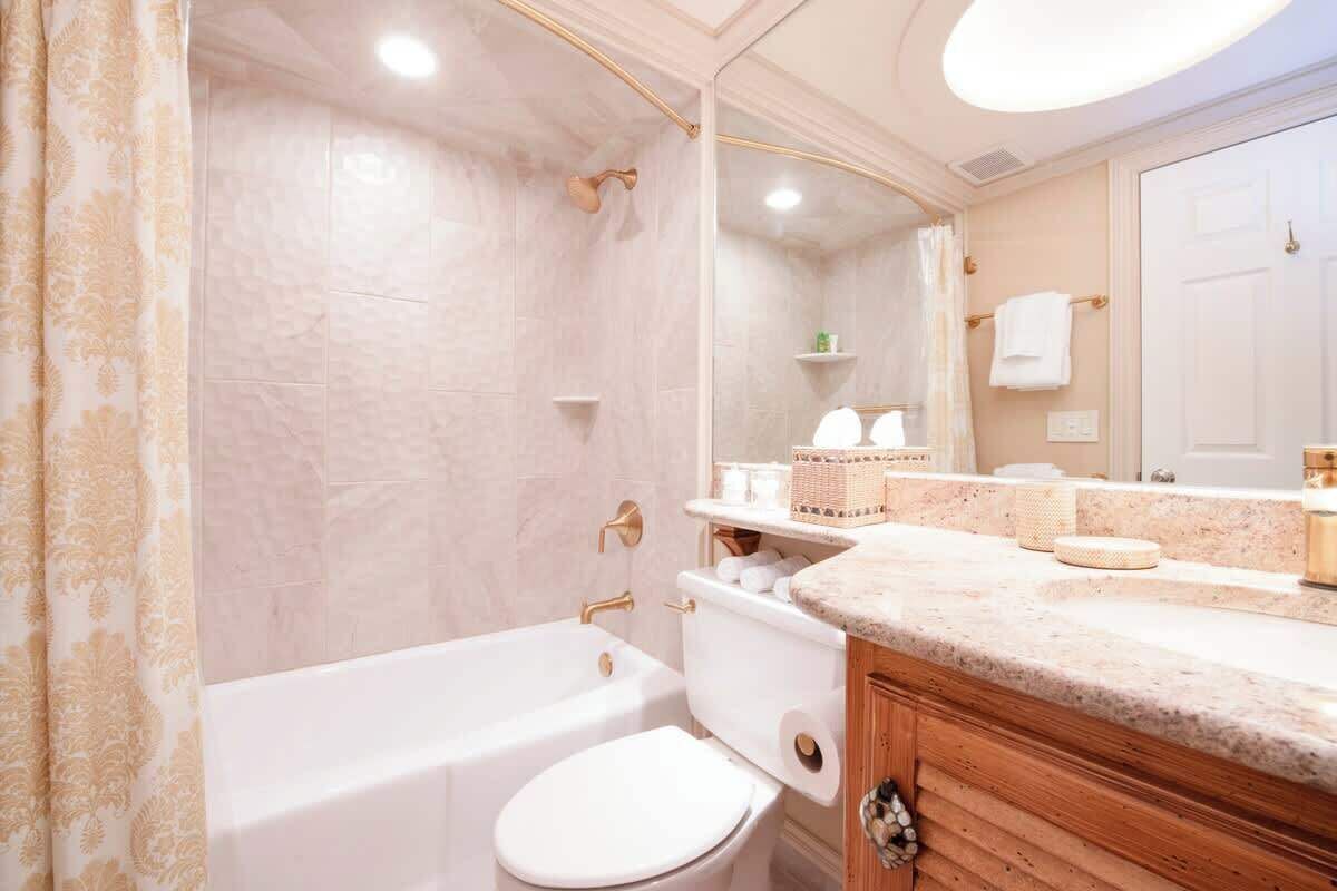 A bathroom with a bathtub, toilet, and vanity with a mirror.
