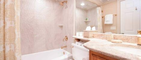 A bathroom with a bathtub, toilet, and vanity with a mirror.