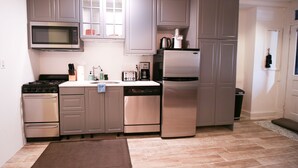 A compact kitchen with stainless steel appliances, grey cabinets, and a small window. - Capitol Hill 2 Bedroom, 6ppl, Patio, Free Parking, near Capitol, Eastern Market (Washington)