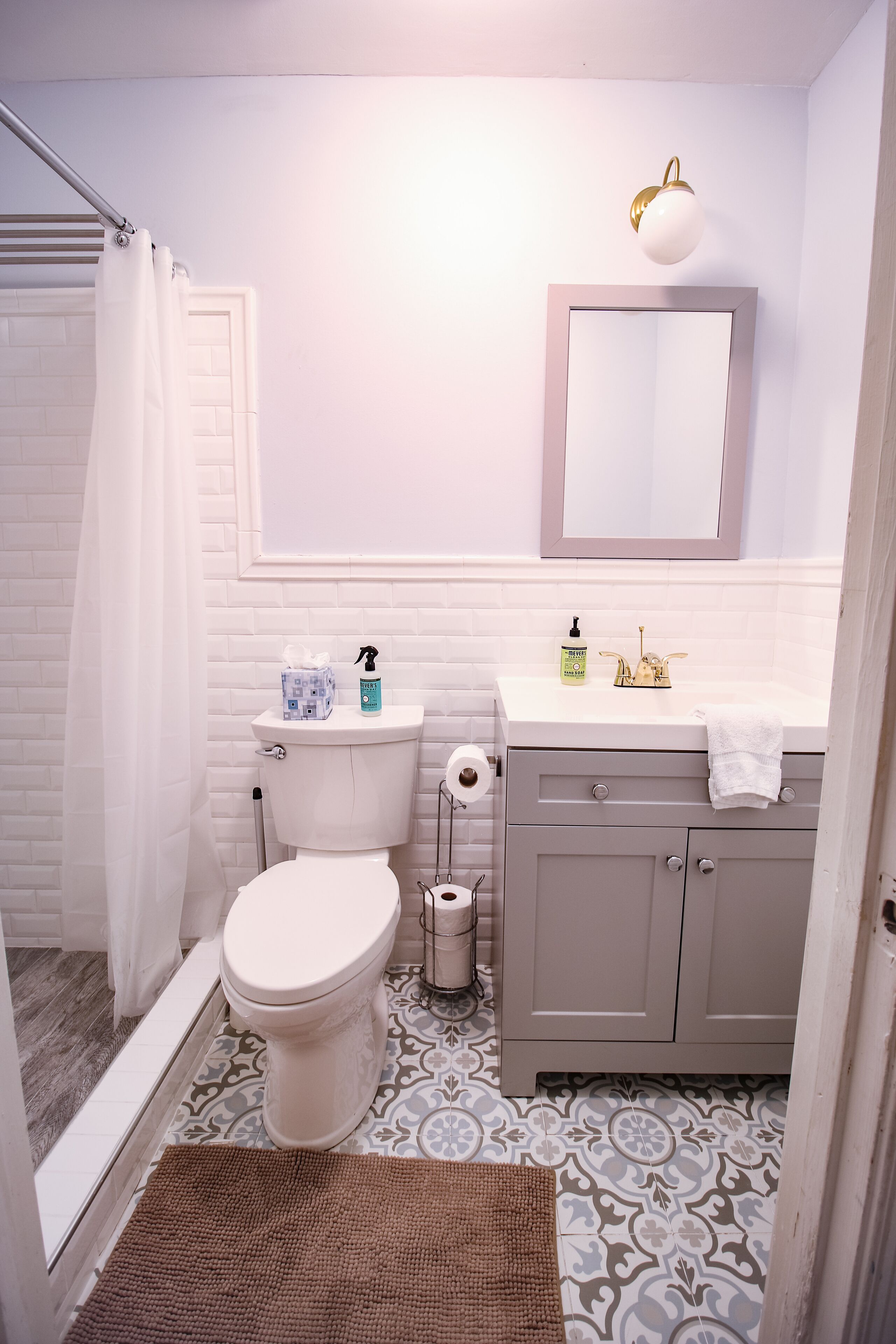 Een badkamer met toilet, wastafel, spiegel en douchegordijn.