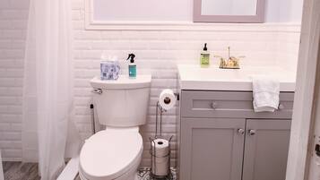 Een badkamer met toilet, wastafel, spiegel en douchegordijn.