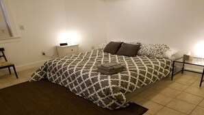 A neatly made bed with patterned bedding, a bedside table with a lamp, and a chair. - Capitol Hill 2 Bedroom, 6ppl, Patio, Free Parking, near Capitol, Eastern Market (Washington)