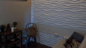 A cozy living room with a sofa, a small table with decorative items, a chair, and a textured wall. - Walking distance to Old SJ, Cruise Ports & Beaches - WIFI - Queen size bed - (San Juan)