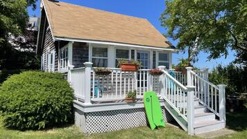 Charming single-story house with a sloped roof and lush green surroundings, perfect for outdoor enthusiasts.