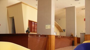 Un vestíbulo con mostrador de recepción, una escalera y zonas de estar.