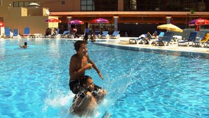 Una piscina con agua cristalina azul, rodeada de sillones de playa y sombrillas.