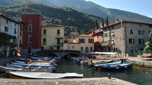 A canal with boats docked, a bridge, and buildings with balconies.