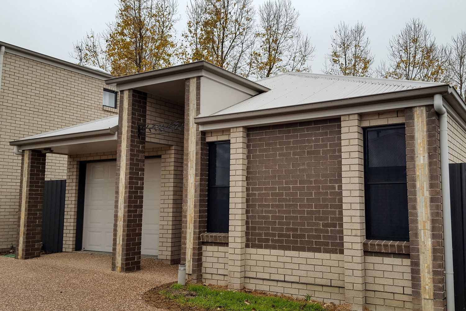 A two-story house with a brick exterior, a garage, and a covered porch.