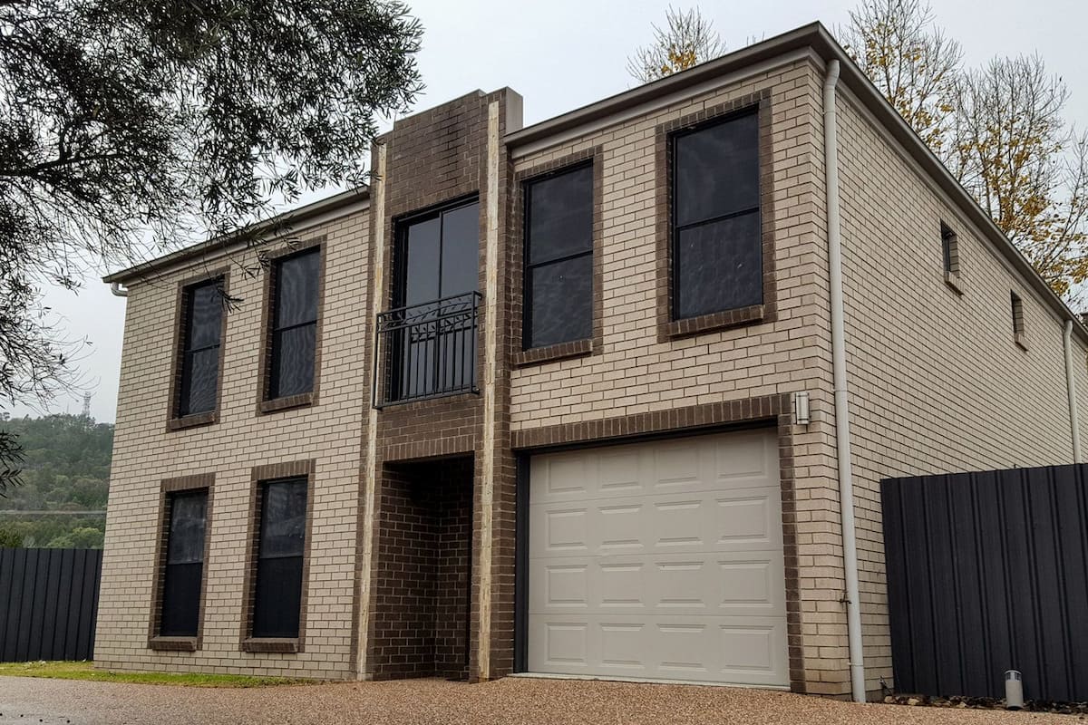A two-story building with a garage, large windows, and a small balcony.