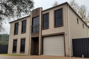 Een gebouw met twee verdiepingen, een garage, grote ramen en een klein balkon.