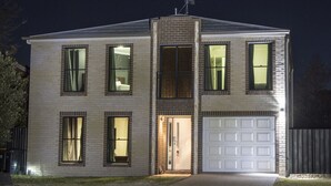 A two-story house with a garage, large windows, and a satellite dish.