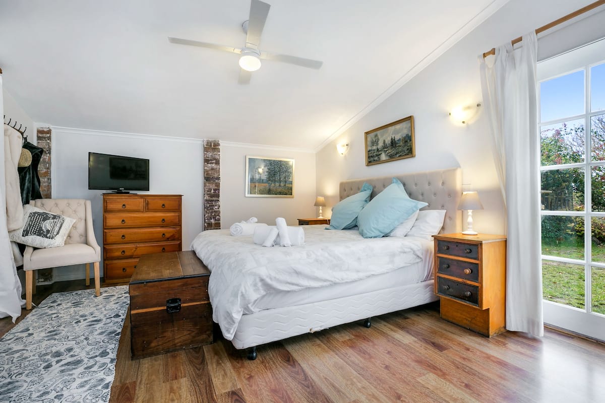 Un dormitorio con cama, cómoda, televisor y ventana con vista.