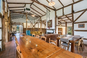 A rustic dining area with a long wooden table, wicker chairs, and a blue sofa. - Taradale House Estate (Taradale)